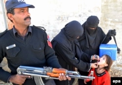 Офицер полиции охраняет врачей, делающих прививки от полиомиелита. Кветта, декабрь 2014 года