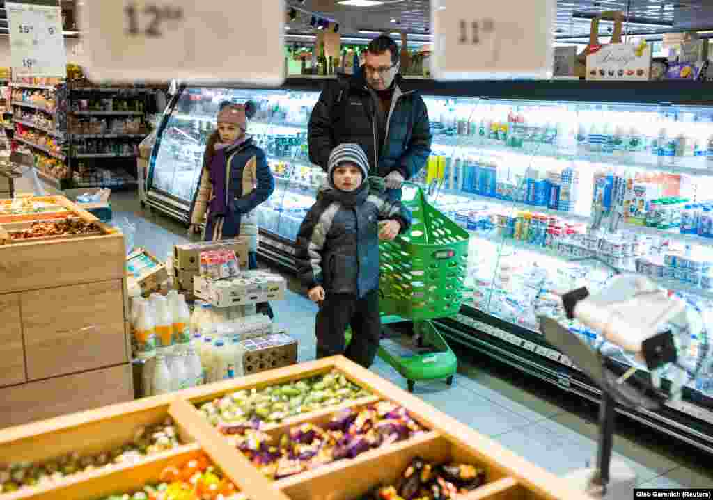 Rozumiy shopping for groceries with his two children. The doctor has his own struggles with finances, earning the equivalent of just $230 per month.