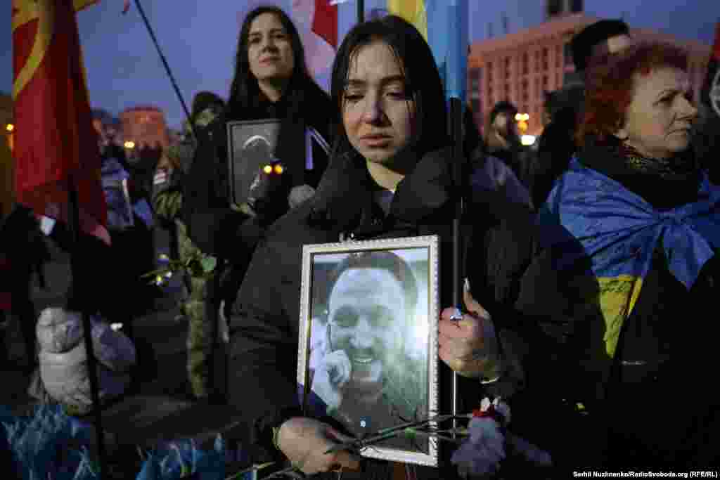 Молода жінка тримає портрет загиблого добровольця Олександра Стасевіча. У бійця залишилися дружина та двоє дітей. За словами його друга&nbsp;Ярослава Гришина, &laquo;Олександр був не зобов&rsquo;язаний воювати за Україну, неодноразово поранений та контужений,&nbsp;міг з чистою совістю демобілізуватися&raquo;, однак &laquo;не міг залишити свій підрозділ та побратимів&raquo;