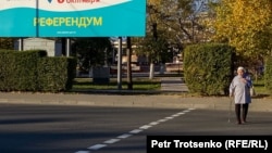 Референдум туралы баннердің жанына өтіп бара жатқан тұрғын. Көрнекі сурет .