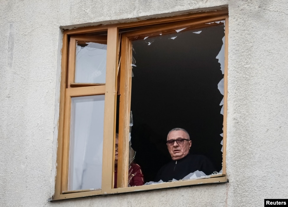 Një banor i Harkivit shikon nga një dritare e thyer nga sulmet e Rusisë në Ukrainë, më 25 mars 2026.