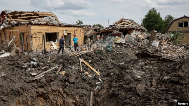 Люди стоять біля зруйнованих житлових будинків на місці російського ракетного удару у місті Покровськ Донецької області. 24 червня 2024 року