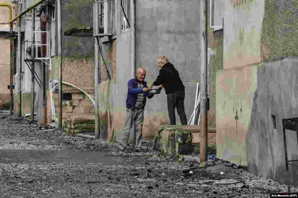 Neighbors share food outside a damaged apartment block in Stepanakert on October 8.