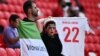 An Iranian fans hold a "Woman. Life. Freedom" flag and a shirt in memory of Mahsa Amini before the Iran-Wales match on November 25.