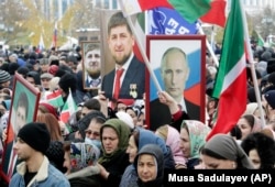 Két jó barát: grozniji lakosok Vlagyimir Putyin orosz elnök és Ramzan Kadirov csecsen vezető portréját tartják a nemzeti egység napja alkalmából tartott gyűlésen Groznijban 2019. november 4-én