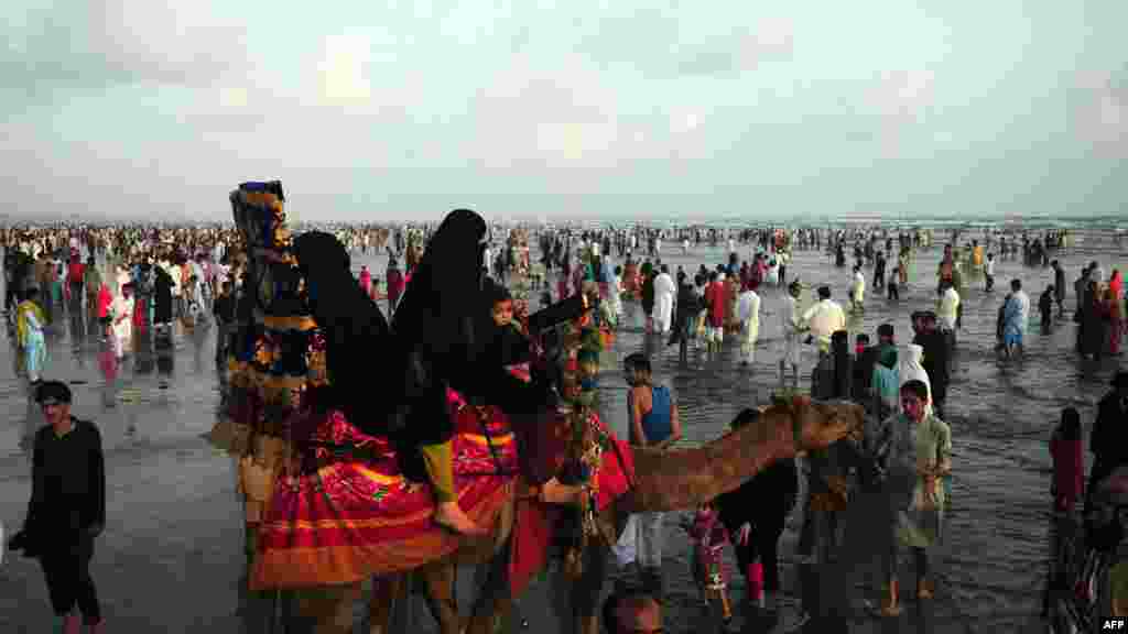 A family rides on a camel at Clifton beach to celebrate the second day of Eid al-Fitr in Karachi, Pakistan. (AFP/Asif Hassan)