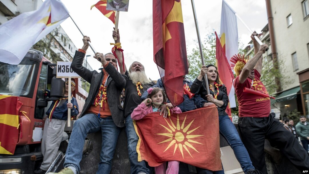 Macedonian protesters wave flags while riding an excavator during a demonstration against a deal to form a new government between the Social Democrats and ethnic Albanian parties. (file photo)