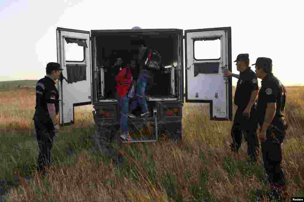 Migrants climb into a police vehicle after being rounded up near Presevo.