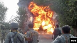 Afghan police stand by as flames rise from an oil tanker hit by militants in Konduz, northern Afghanistan on October 2.