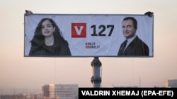 Workers in the Kosovar capital, Pristina, install a giant election poster showing prime ministerial candidate Albin Kurti (right) and acting President Vjosa Osmani. 