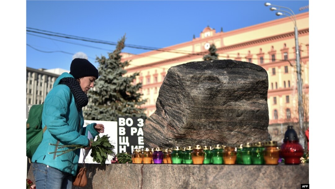 A woman places a candle and flowers at the memorial to the victims of Soviet-era political repression in Moscow. New polls show that 50 percent of Russians believe they may see similar political repressions again in their lifetime.