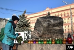 A woman places a candle and flowers at the memorial to the victims of Soviet-era political repression in Moscow. New polls show that 50 percent of Russians believe they may see similar political repressions again in their lifetime.