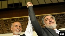 Afghan presidential candidates Ashraf Ghani (L) and Abdullah Abdullah raise their hands during a press conference in Kabul, July 12, 2014.