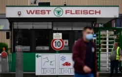 A worker passes the entrance of the Westfleisch meat-processing company in Hamm near Coesfeld, Germany, on May 10.