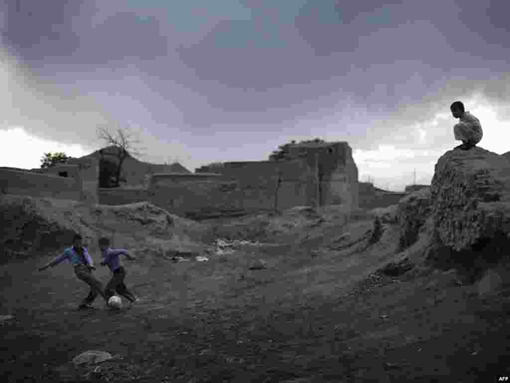 Afghan boys play soccer near ruined buildings in the early evening in the old part of Kabul. - Photo by Mauricio Lima for AFP