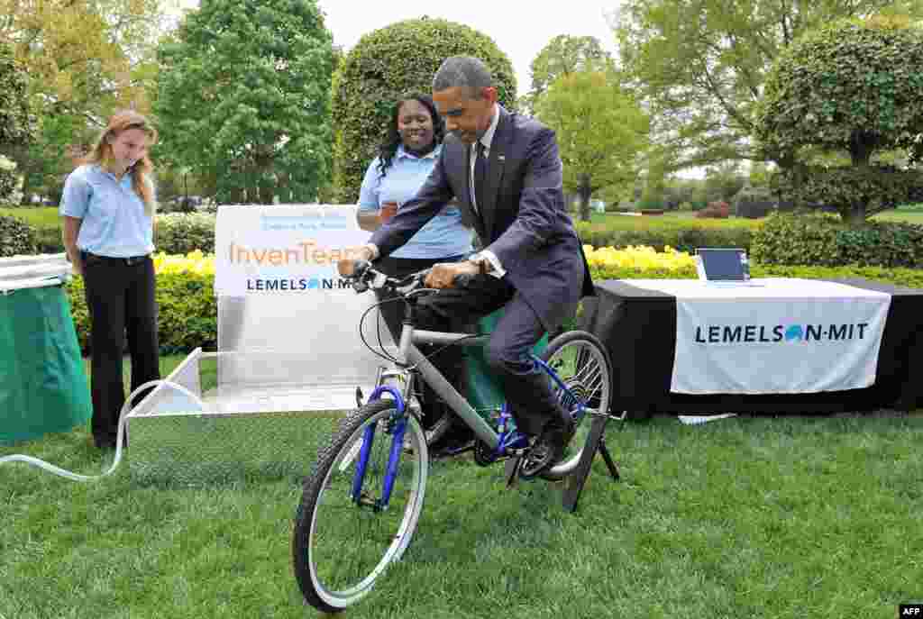 U.S. President Barack Obama pedals a bicycle-powered emergency water sanitation system as he visits science fair projects in the East Garden of the White House in Washington. Obama hosted the White House Science Fair and celebrated the student winners of a broad range of science, technology, engineering, and math competitions from across the country. (AFP/Jewel Samad)