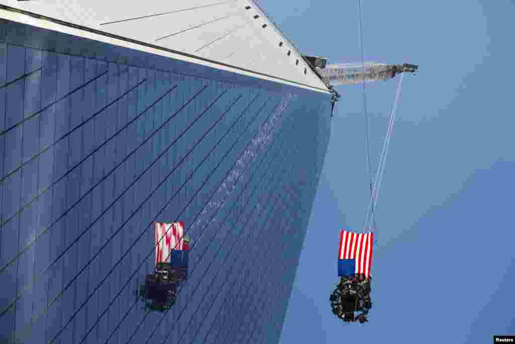 A U.S. flag flies in the wind as the final piece of a spire is lifted to the top of One World Trade Center in New York. (Reuters/Lucas Jackson)