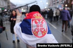 Një pjesëmarrëse bart flamurin serb teksa merr pjesë në tubimin në Jagodinë.