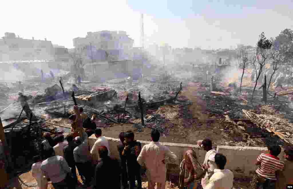 People search for their belongings amid the debris of their houses after a large fire broke out, destroying over 100 homes in a slum area of Karachi on November 5. (epa/Rehan Khan)