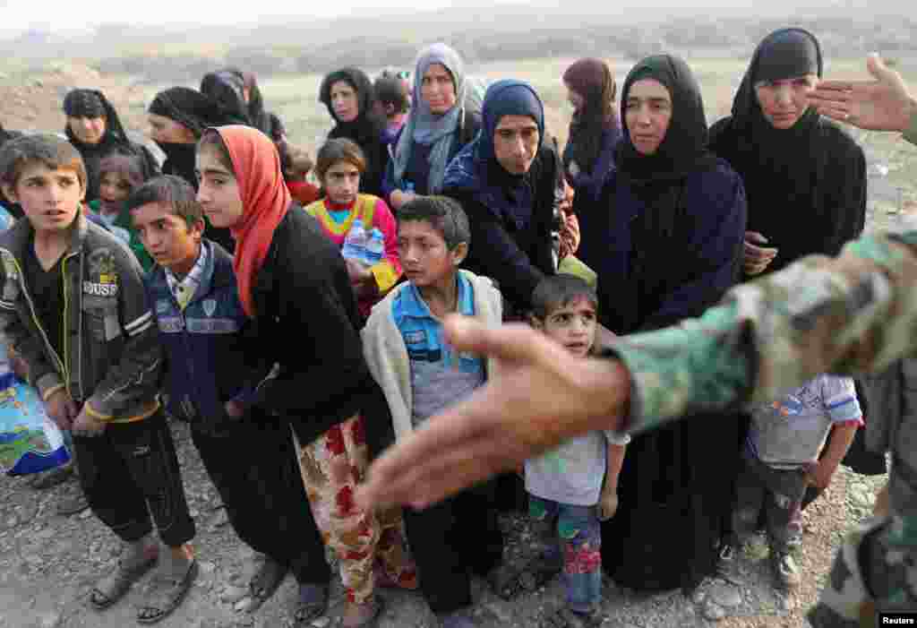 Also near Hassan Sham, a Kurdish Peshmerga gestures in front of internally displaced women on October 25. (Reuters/Goran Tomasevic)