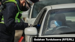 Инспектор проверяет документы водителя. Бишкек. 31 марта 2020 года.