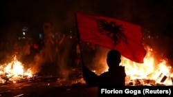 Një person duke valëvitur një flamur kombëtar shqiptar teksa studentë zhvillonin protestë antiqeveritare në Tiranë, Shqipëri, më 13 tetor 2026.