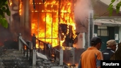 Men walk past a burning building in the Kyrgyz city of Osh on June 11.