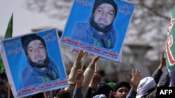 Pakistani supporters of former police bodyguard Mumtaz Qadri hold posters bearing his image as they gather outside the High Court in Islamabad, on March 9.