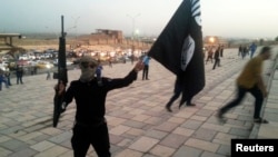 «Ирак пен Шам ислам мемлекеті» (ИЛИМ) ұйымының туын ұстап тұрған қарулы адам. Мосул, Ирак, 23 маусым 2014 жыл.