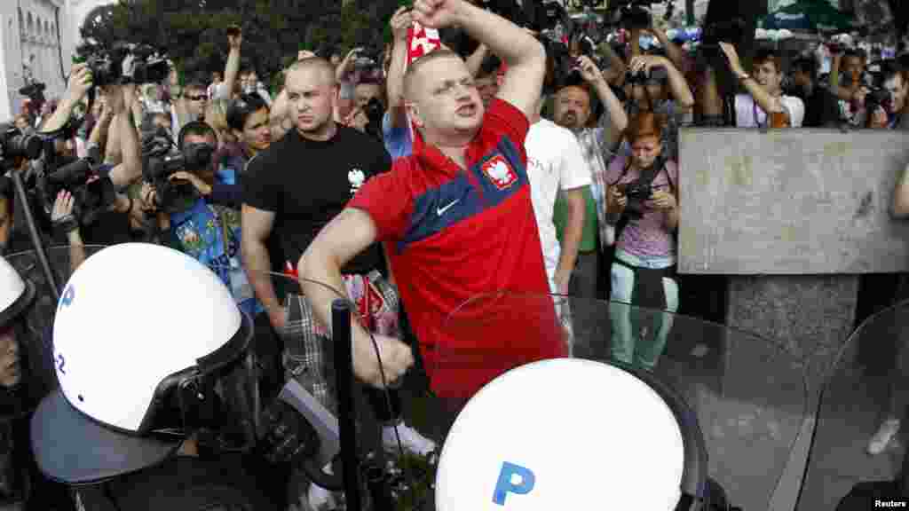 Polish soccer fans shout at Russian supporters as they walk protected by Polish riot police in Warsaw.