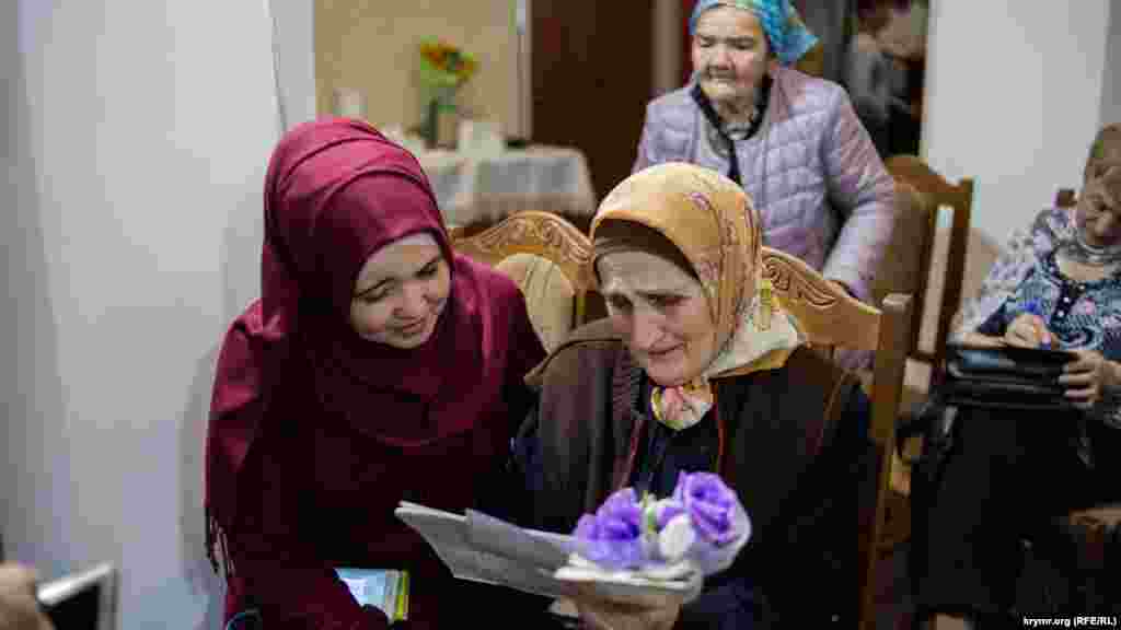 Мать Руслана Сулейманова рассматривает открытку с фотографией своего сына