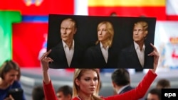 Një gazetare në Rusi mban portretet e presidentit rus, Vladimir Putin, lideres së Frontit Kombëtar në Francë, Marine Le Pen, dhe presidentit të SHBA-së, Donald Trump.