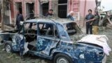 AZERBAIJAN -- People stand next to a destroyed car in a damaged area of the city of Ganca following a reportedly Armenian rocket strike,n October 4, 2020
