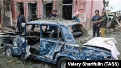 AZERBAIJAN -- People stand next to a destroyed car in a damaged area of the city of Ganja following a reportedly Armenian rocket strike, October 4, 2020