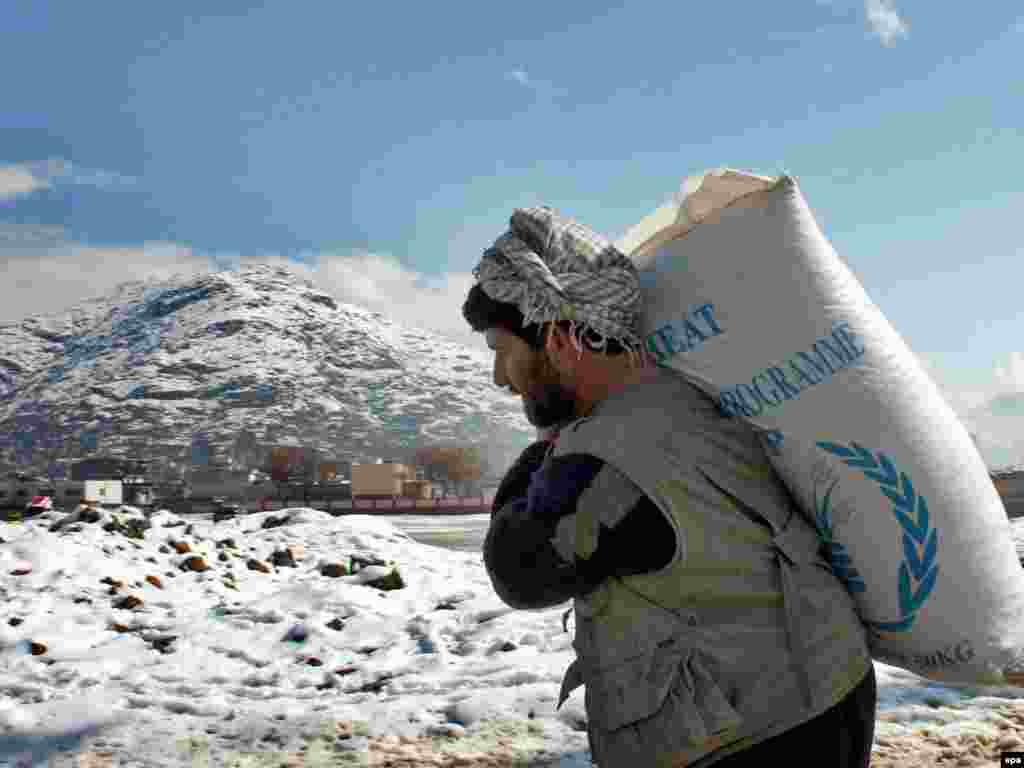 A man carries flour distributed by the World Food Program on a snow-covered path in Kabul.