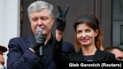 Former Ukrainian President Petro Poroshenko addresses supporters as his wife, Maryna, flashes the victory sign outside a court building in Kyiv on June 18.