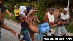 Opposition demonstrators carry an injured protester on the Brazilian side of the border between Venezuela and Pacaraima, Roraima state, Brazil, where clashes erupted amid efforts to take aid into the crisis-hit country, on February 23, 2019. 