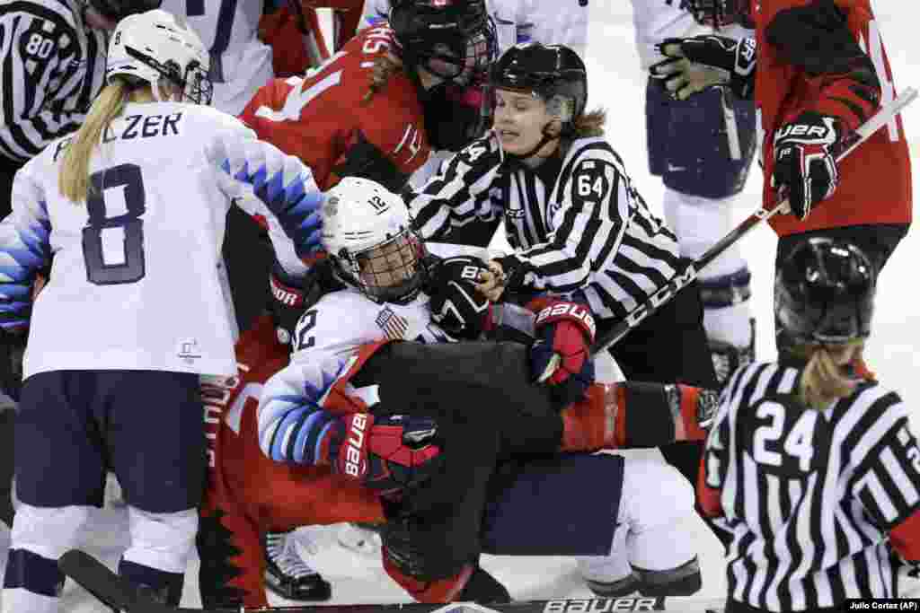 Хокей: суддя Дженні Гейкіннен (64) із Фінляндії намагається роз&rsquo;єднати Келлі Паннек (12) зі Сполучених Шататів та Лауру Стейсі (7) із Канади, хокеїсти зчепилися під час третього періоду попереднього туру жіночої хокейної гри. Канада виграла 2-1