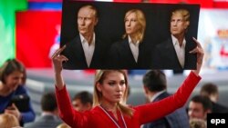 O jurnalistă, ținând un poster cu portretele lui Vladimir Putin, Marine Le Pen și Donald Trump, înaintea conferinței de presă anuale a liderului de la Krenlin