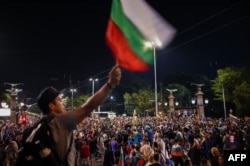 Протестувальник махає болгарським прапором, коли люди збираються на антиурядову демонстрацію в центрі Софії, Болгарія, 7 серпня 2020 року