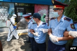 Оппозиция ұйымдастырған митинг кезінде полицейлер жетектесіп көшені жапты, жұмысшылар залалсыздандыру жұмысын жүргізді. Алматы, 6 маусым 2020.