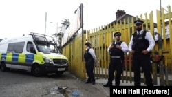 Police officers stand outside a property that was raided in Newham, East London, on June 5, as part of the investigation into the London attacks on June 3.