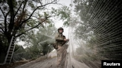 Український військовий встановлює сітки проти дронів над дорогою в Костянтинівці Донецької області, 19 вересня 2025 року