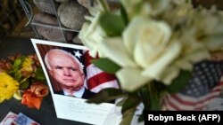 U.S. -- Photographs, flowers and notes gather at a makeshift memorial to US Senator John McCain outside his office in Phoenix, Arizona, August 26, 2018