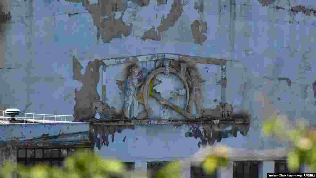 На фасаде сохранился необычный логотип: силуэт Крымского полуострова в обрамлении перевернутого серпа и молота, поддерживаемых с двух сторон рабочими