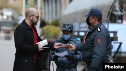 Armenia -- Police officers check documents of a man in Yerevan as part of a coronavirus lockdown imposed by the government, March 25, 2020.