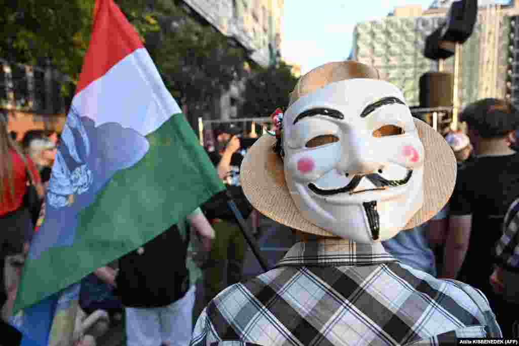 A demonstrator holds a Hungarian flag and a Guy Fawkes mask as teachers, students, and otherers protest in central Budapest at the headquarters of the Interior Ministry on September 2 after a high school principal was fired for not implementing a government-mandated &quot;smartphone ban.&quot;