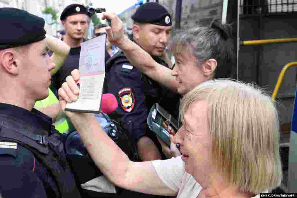 A woman shows her ID to police officers, who were criticized by one civil rights activist for randomly stopping and detaining people &quot;for no reason.&quot;