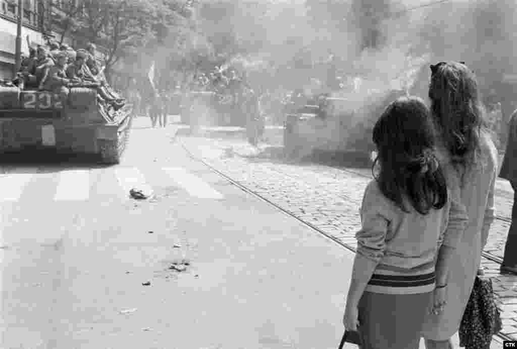 Young women watch as tanks approach the state radio headquarters.