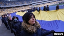 Locuitori din Kiev poartă steagul național ucrainean pe Stadionul Olimpic, pentru a marca „Ziua Unității”, pe 16 februarie 2022, ziua în care agențiile de informații occidentale ar fi spus că vor fi invadați de Rusia.